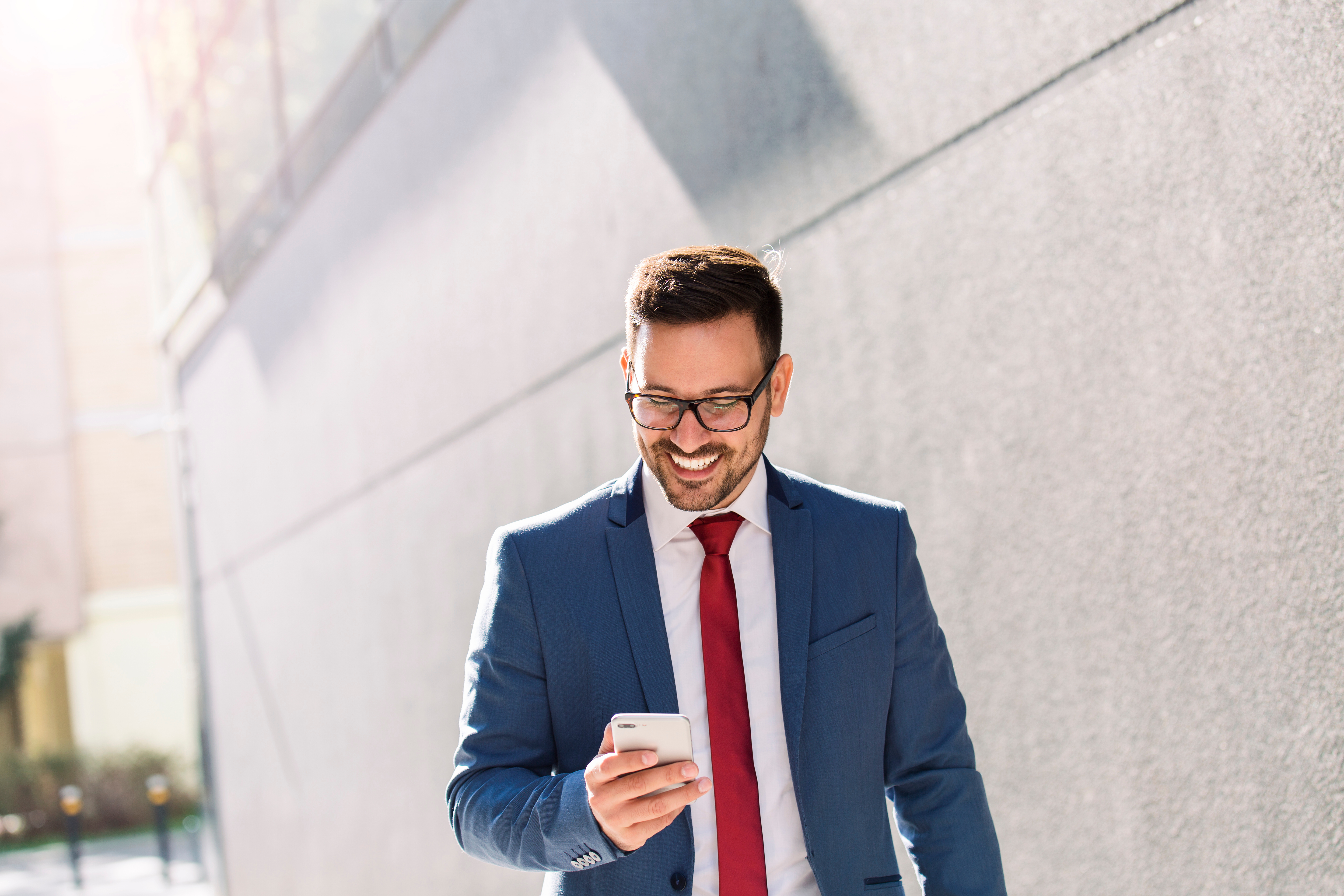 photo of a man in blue suit, red tie and glasses looking at this phone
