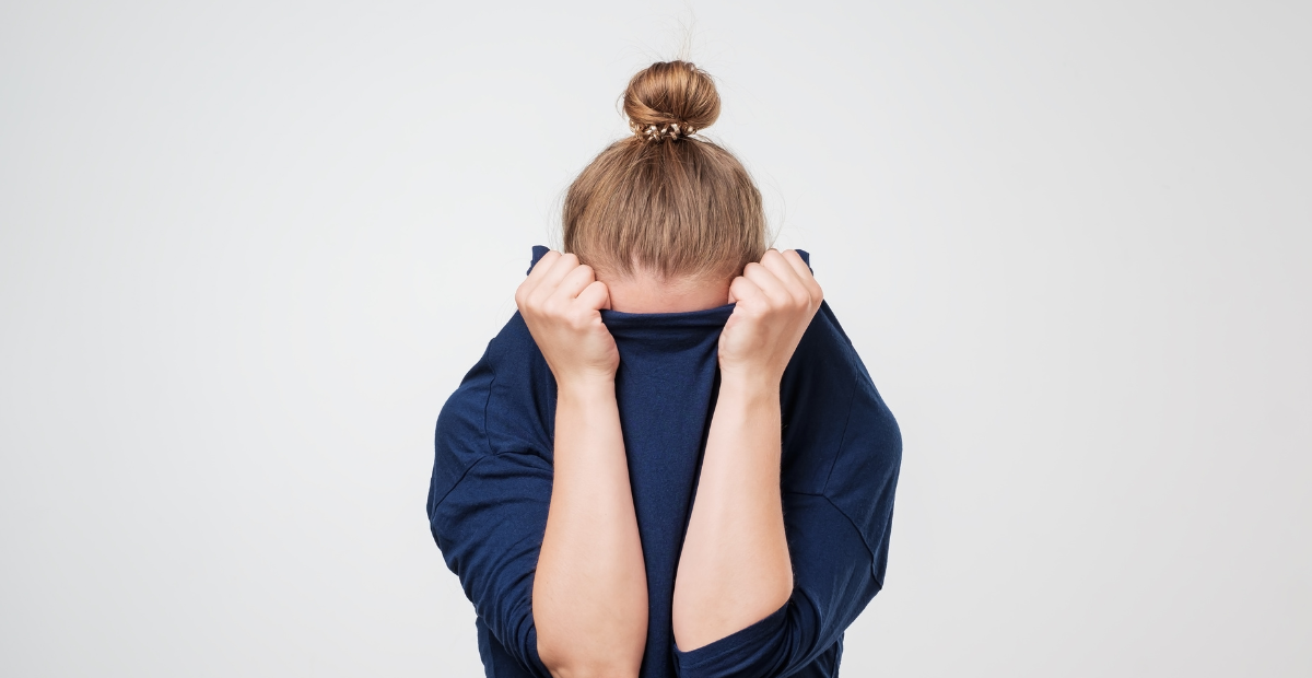 women pulling jumper over her face in fear